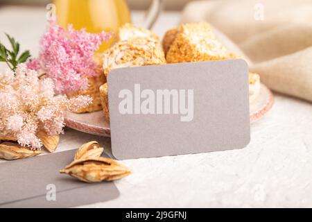 Gray business card with traditional turkish delight (rahat lokum) on white ceramic bowl on a gray concrete background. side view, close up. Stock Photo