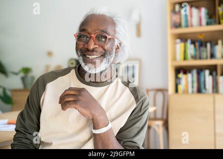 Smiling senior man sitting in living room Stock Photo