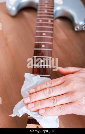 Guitar master polishing fretboard of electric guitar, close up shot of hands with cloth Stock Photo