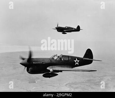 Vintage photo circa February 1943 of a pair of American P-40 single-engine fighter planes in flight. It served with the RAF (Royal Air Force) and with the AVG (American Volunteer Group or Flying Tigers) in China and with the US army air force in the Pacific Stock Photo