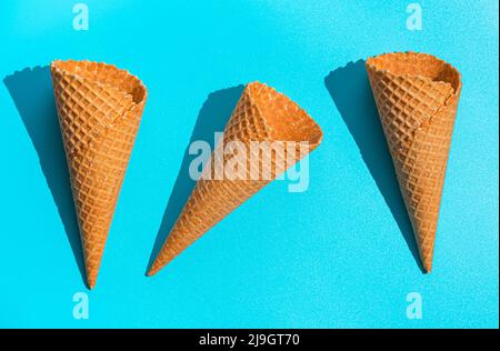 Three waffle ice cream cups on a blue background in hard light. Stock Photo