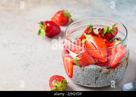 Homemade chia pudding with strawberry and syrup in glass jar, gray background, copy space. Vegan breakfast concept. Stock Photo