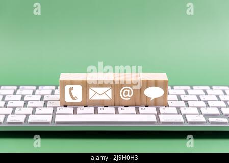 Contact us icon on wood block on top of computer keyboard - business concept Stock Photo