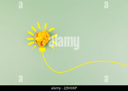 Crumpled paper ball light bulb on green background Stock Photo