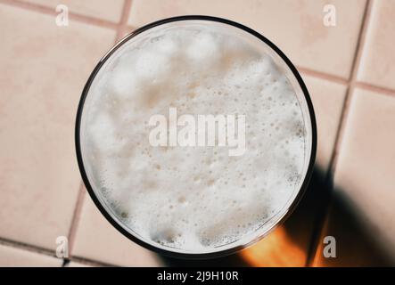 Glass of fresh lager beer with White fresh Foam on table. Beer foam top view. Bubble froth of beer. Stock Photo