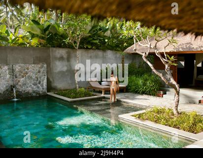 Woman entering pool of Bile Deluxe Pool Villa, a private pool villa at Kayumanis Ubud, Bali, Indonesia. Stock Photo