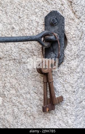 Antique rusty iron keys hanging on a granite wall Stock Photo