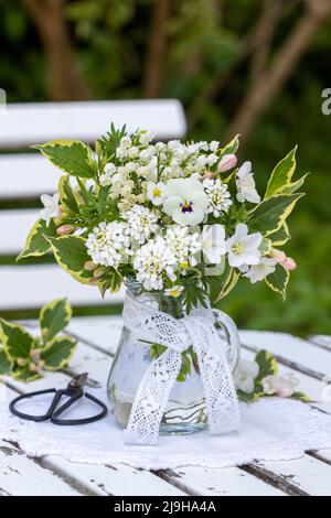 bouquet of white spring flowers in glass vase in garden Stock Photo