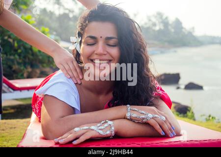 Female beautician doctor with patient make procedure to beautiful indian girl.close up portrait of asian woman closed eyes and white smile wellness Stock Photo