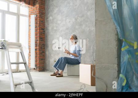 Woman taking lunch break sitting on box in front of wall Stock Photo