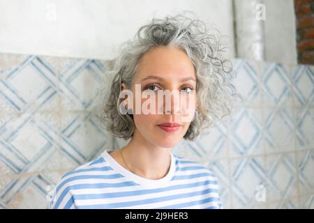Woman with gray hair standing in front of wall Stock Photo