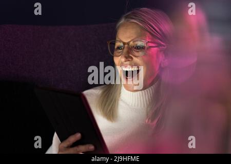 Laughing senior woman looking at tablet PC Stock Photo