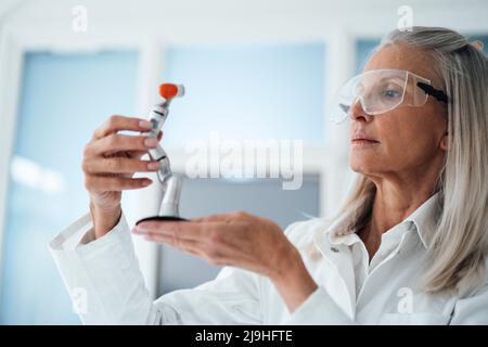 Female engineer examining robotic arm at workshop Stock Photo
