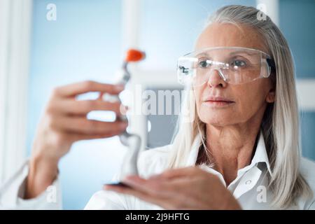 Engineer with protective eyewear looking at robotic arm in workshop Stock Photo