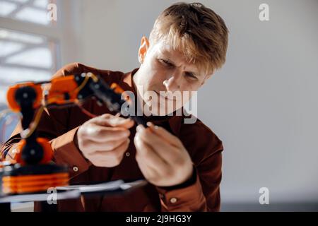 Businessman examining model of robotic arm in office Stock Photo