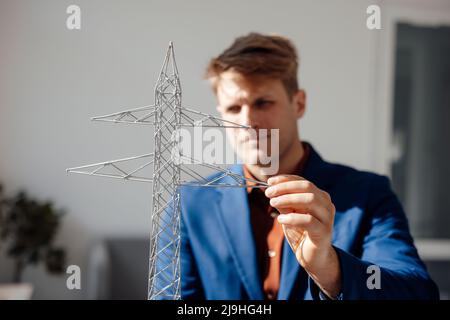 Businessman looking at electricity pylon model in office Stock Photo