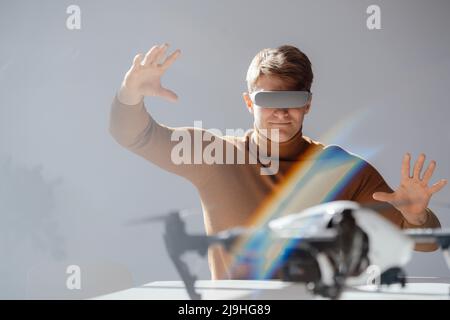 Smiling businessman wearing virtual reality simulator gesturing sitting at desk in office Stock Photo