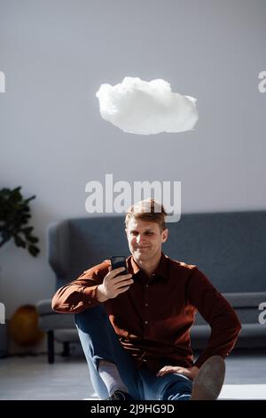 Smiling businessman using smart phone sitting under levitating cloud network in office Stock Photo