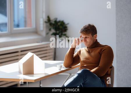 Thoughtful architect looking at model house in office Stock Photo