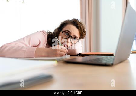 Tired woman using laptop studying at home Stock Photo