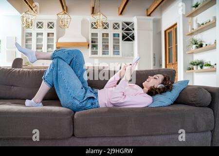 Woman using smart phone lying on sofa Stock Photo