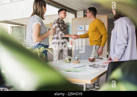 Two businessmen shaking hands in office Stock Photo