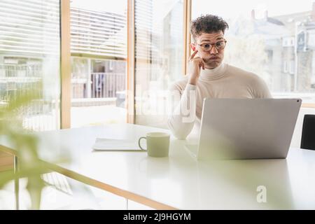 Stressed young businessman using laptop at desk in office Stock Photo