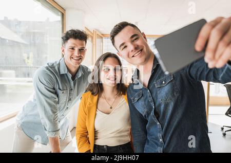 Smiling business people taking a selfie in office Stock Photo