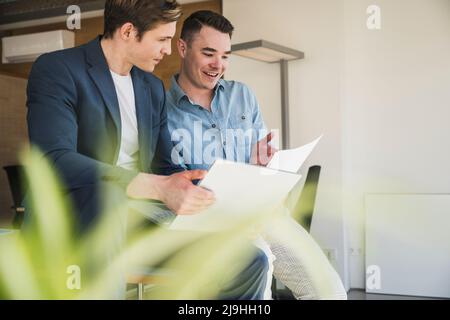 Two happy colleagues with laptop and documents in office Stock Photo