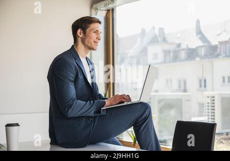 Businessman using laptop at the window in office Stock Photo