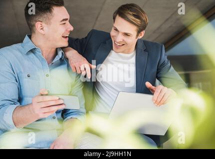 Two happy colleagues sharing smartphone in office Stock Photo