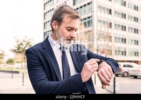 Businessman checking time on smart watch Stock Photo
