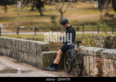 Cyclist using mobile phone leaning on wall Stock Photo
