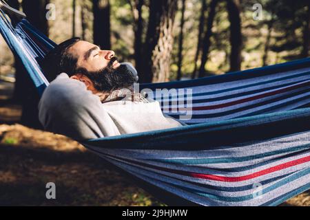 Bearded man with eyes closed resting in hammock Stock Photo