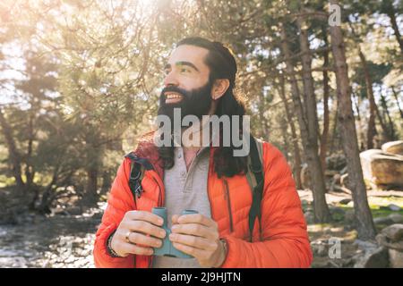 Smiling bearded man holding binoculars standing in forest Stock Photo