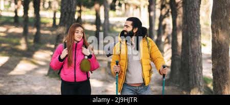 Smiling bearded man talking with girlfriend trekking in forest Stock Photo