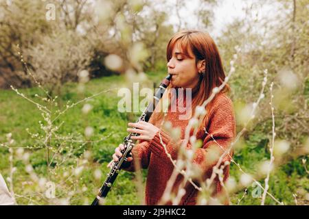 Woman playing clarinet by plants in field Stock Photo