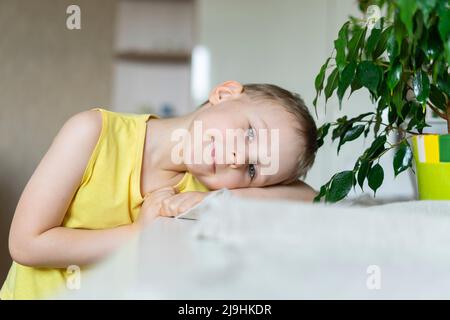 Smiling boy leaning head on table at home Stock Photo