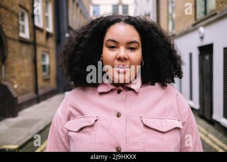 Young woman with curly hair standing on road Stock Photo