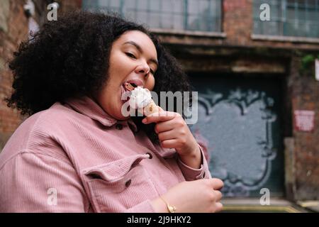 Young woman with curly hair eating ice cream Stock Photo
