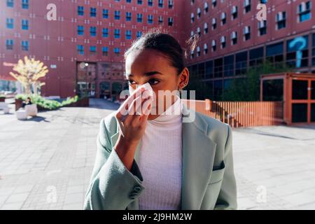 Sad businesswoman wiping tears with tissue in front of office building Stock Photo