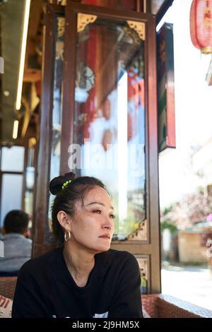 asian woman sitting sadly in a coffee shop with teary eyes Stock Photo