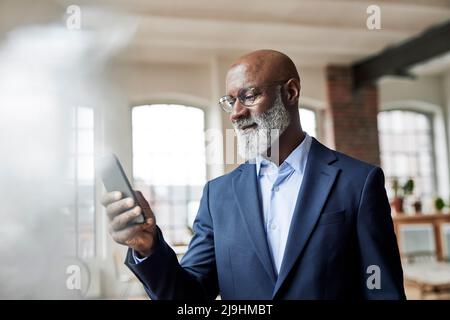 Mature businessman using smart phone at home Stock Photo