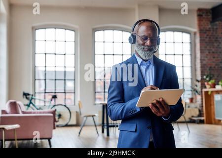 Smiling businessman with headset using tablet computer at home Stock Photo