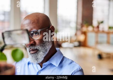 Scientist looking through magnifying glass at home Stock Photo