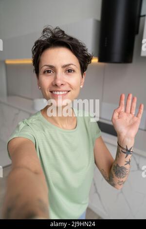Tattooed woman smiling at camera while taking bath with lather in