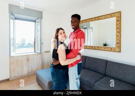 Happy couple hugging each other in living room at home Stock Photo