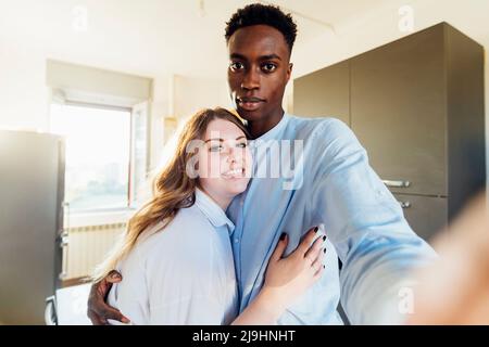 Happy couple taking selfie in kitchen at home Stock Photo