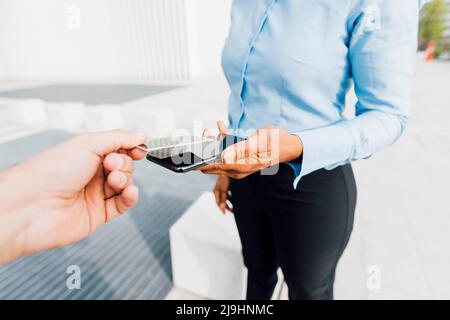 Hand of man holding credit card using tap to pay method with freelancer Stock Photo