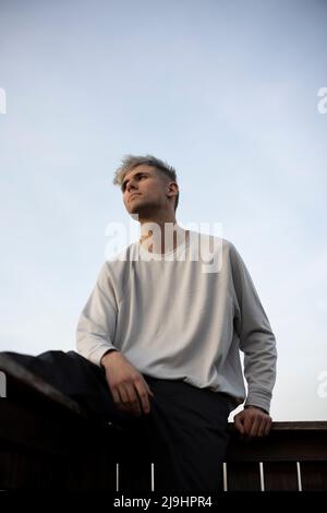 Thoughtful young man sitting on railing Stock Photo
